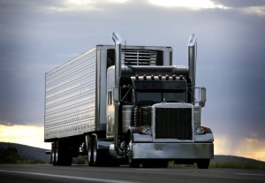 big truck driving on a highway with cloudy sky in background