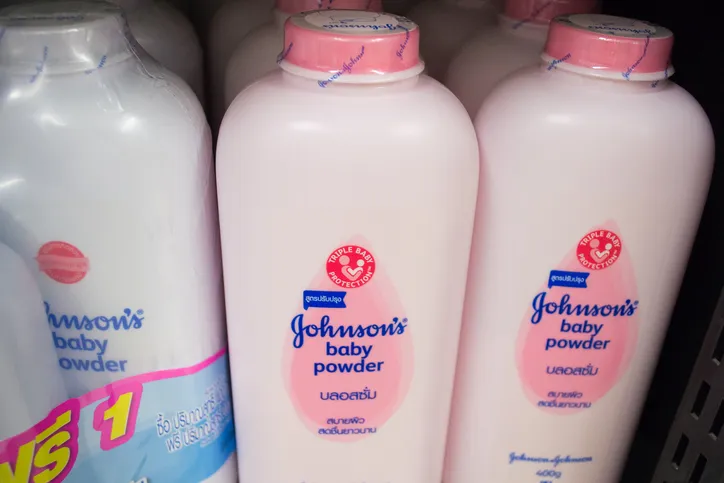 A several bottles of Johnson's Baby Powder on a store shelf, some with pink lids.