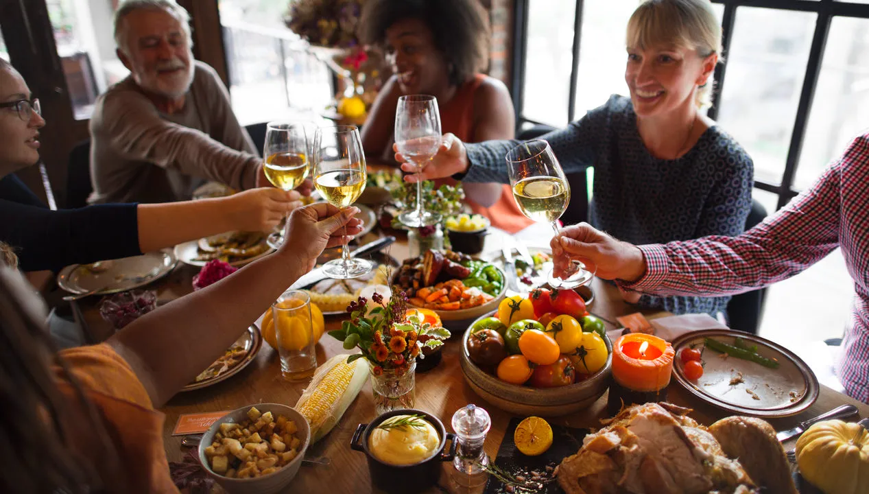 A group of people sitting around in a table with a lot of foods and fruits.