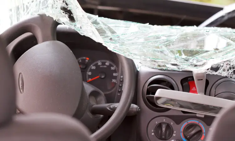 A car featuring a shattered windshield and a damaged dashboard, indicating significant impact or accident damage.