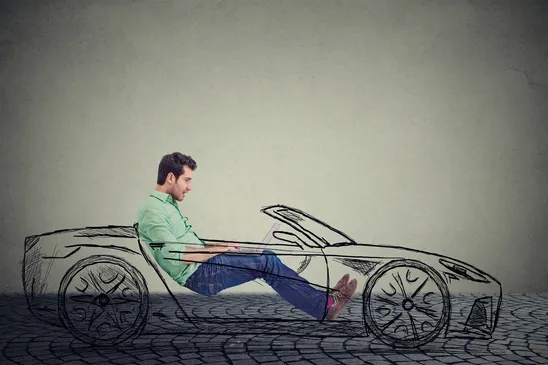 Man uses laptop while driving a sketch of a convertible, representing driverless car technology.