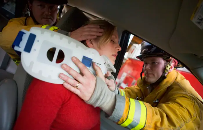 A firefighter supports a woman while a man nearby holds a rescue device, indicating a rescue operation in progress.