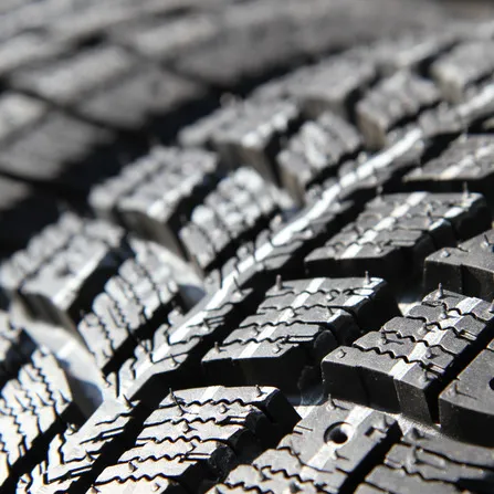 A winter or all-season tire, with visible sipes and small rubber pins.