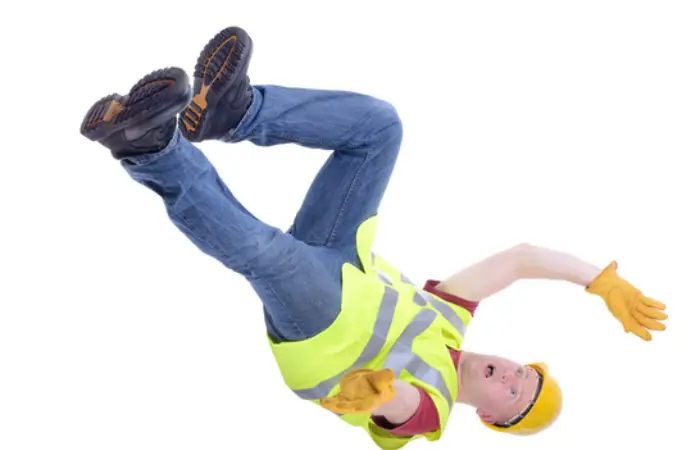 . A man wearing a yellow safety vest is captured mid-fall, showing a surprised expression as he loses his footing.