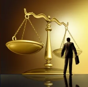 A small silhouette of a lawyer with a briefcase standing before a large, golden scale of justice.
