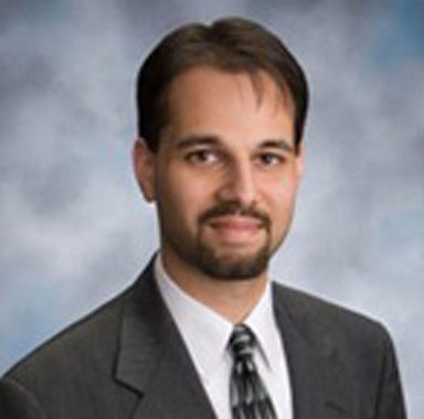 A man in a suit and tie stands confidently