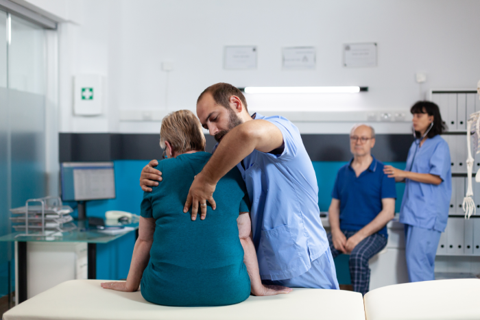 Medical assistant treating woman with back and spine pain for physical recovery. Specialist giving assistance to retired patient with spinal cord injury and osteopathy examination