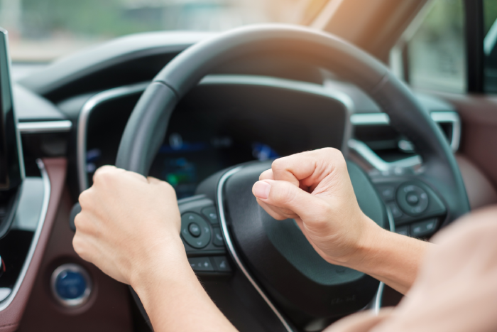 woman driver honking a car during driving on traffic road, hand controlling steering wheel in vehicle. Journey, trip and safety Transportation concepts